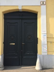 Eine hohe, doppeltürige Eingangstüre in dunkelgrün in einem gelb gehaltenen Haus